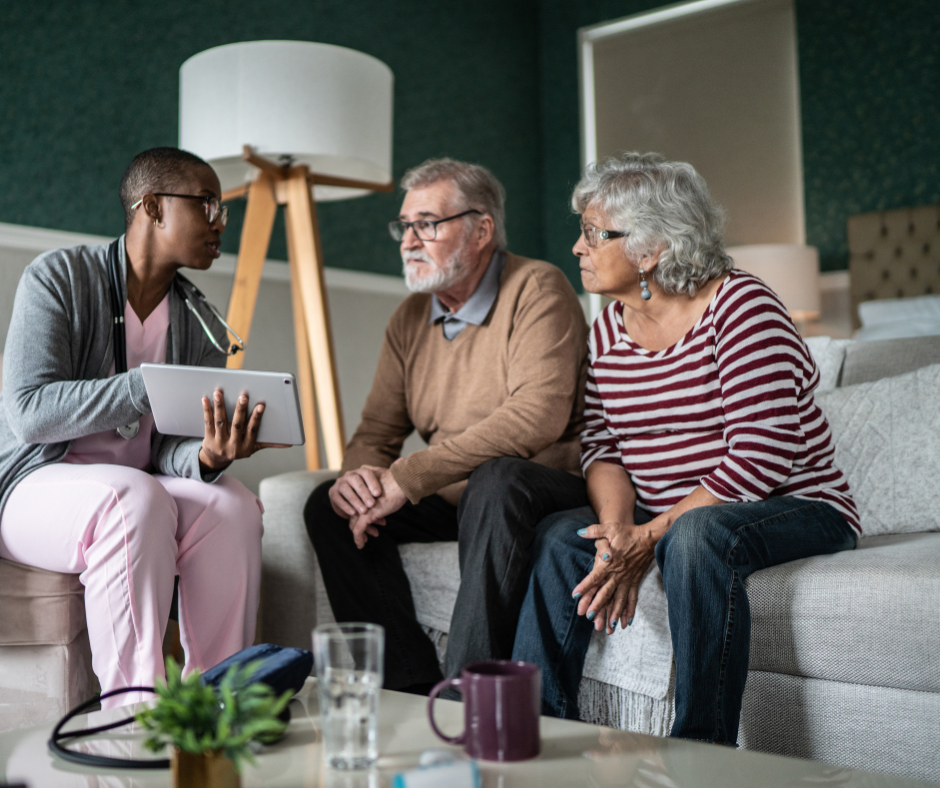 A healthcare professional showing an older couple something on a digital tablet.